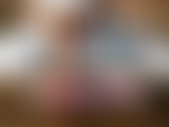 eine person mit jeans sitzend im bett und eine person mit roten Stöckelschuhen davor, nur die Beine sind sichtbar