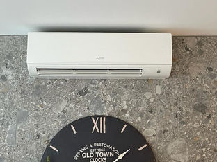 Air con unit on a wall above a clock