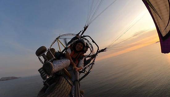 Una chica volando parapente con mucha adrenalina en un atardecer muy lindo sobre la costa verde de Lima