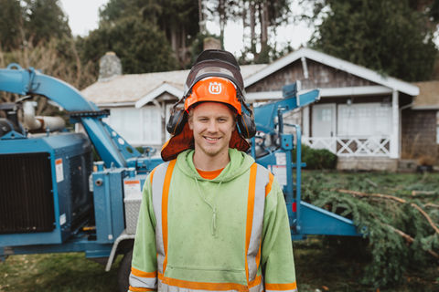 owner of hi-rigger tree service in his work great standing in front of a wood chipper on the job site
