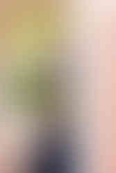 ECU graduate in black dress and cap posing under brick archway on East Carolina University campus.