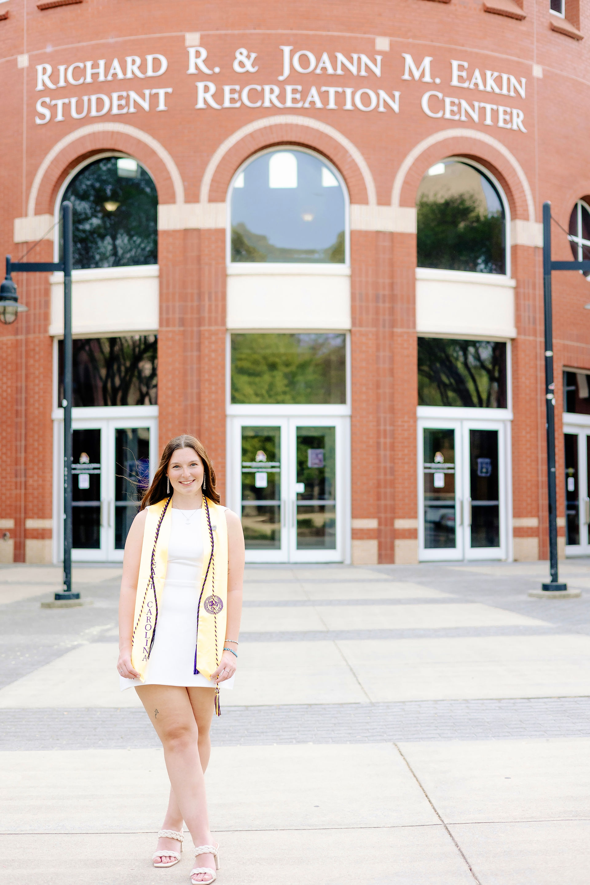 ECU senior posing in front of Student Recreation Center building on East Carolina University campus.