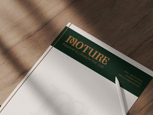 A letterhead on a wooden table with a pencil. It has a green header with text "Moture Apparel & Lifestyle Pvt. Ltd." and contact info.
