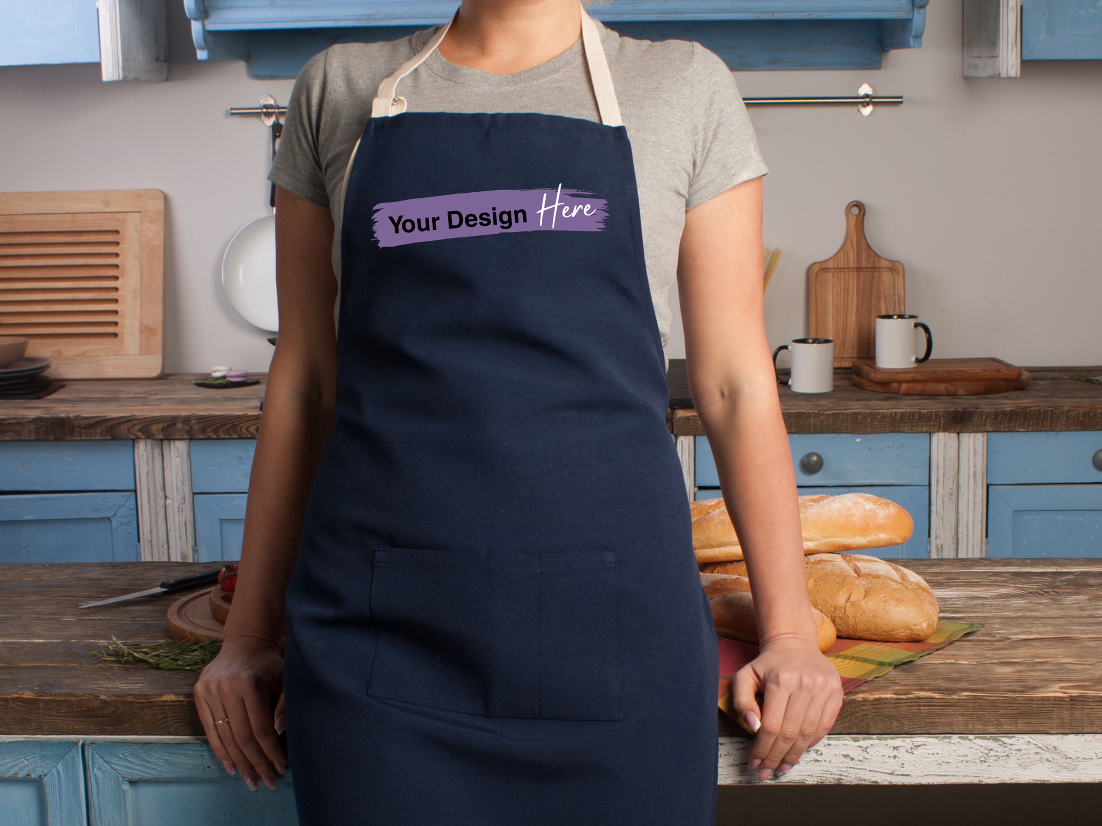 Navy apron with 'Your Design Here' text in a kitchen