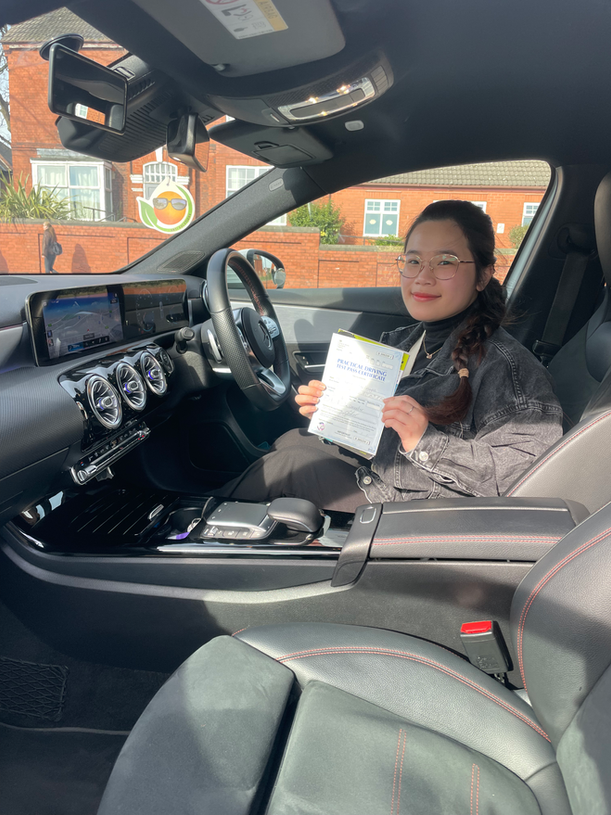 Student holding driving test certificate outside training car
