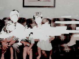 An old, distorted family photo with several people seated together and their faces washed out by bright light.