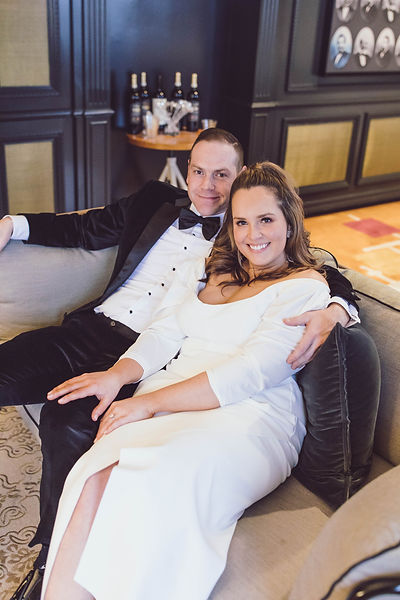 image of bride and groom seated on a couch smiling lovingly at the camera