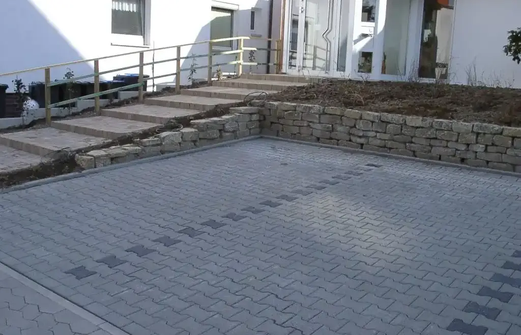 Hofeinfahrt, gepflasterte Parkplätze und Treppe.