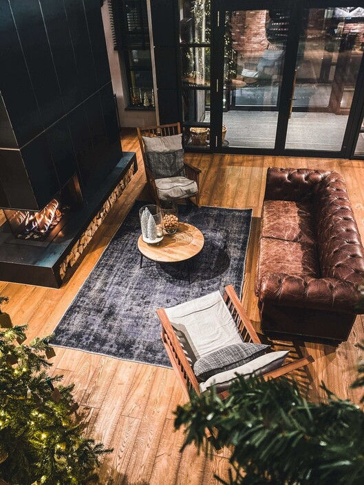 Interiors of a modern mountain home with floor-to-ceiling windows, stone fireplace, and contemporary furnishings