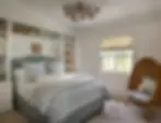 Cozy teenage bedroom with blue gingham bedding, built-in bookshelves, and woven egg chair, featuring cottage-style decor