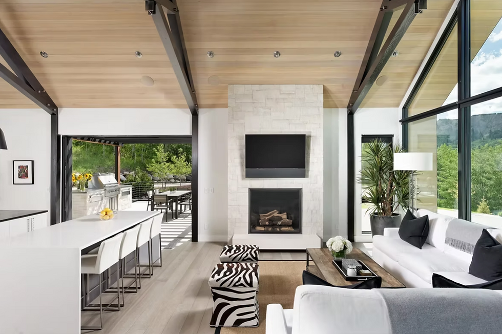White modern Aspen home living room and kitchen highlighting aysmmertrical balance in interior design with a large L-shaped couch balanced with two zebra stools.