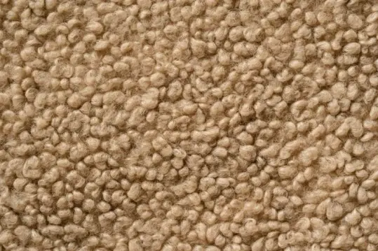 You can see what Bouclé Fabric is made of here, a close-up of beige Bouclé fabric with looped, nubby texture & curled yarn.
