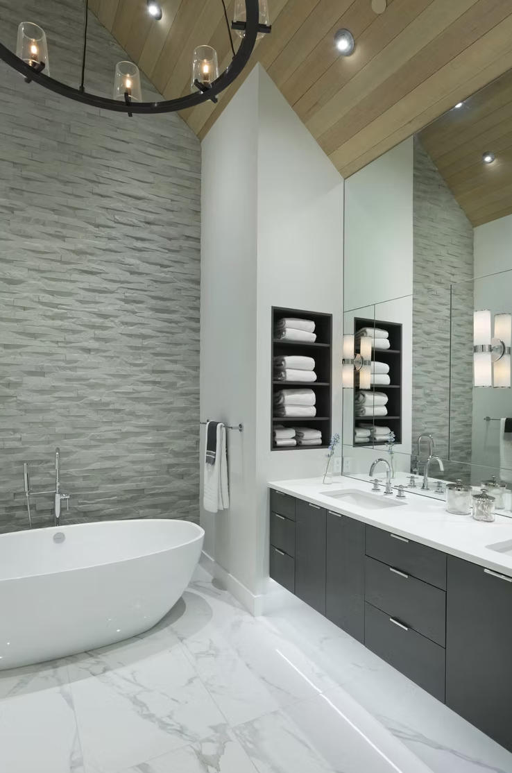 Bright bathroom with freestanding tub and chandelier, with shelving showcasing white towels,