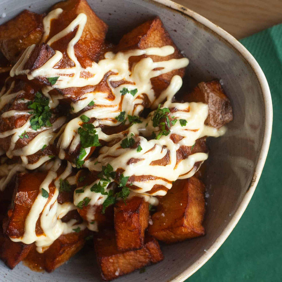 Casa's patatas bravas featuring crispy potatoes with aioli drizzled on top