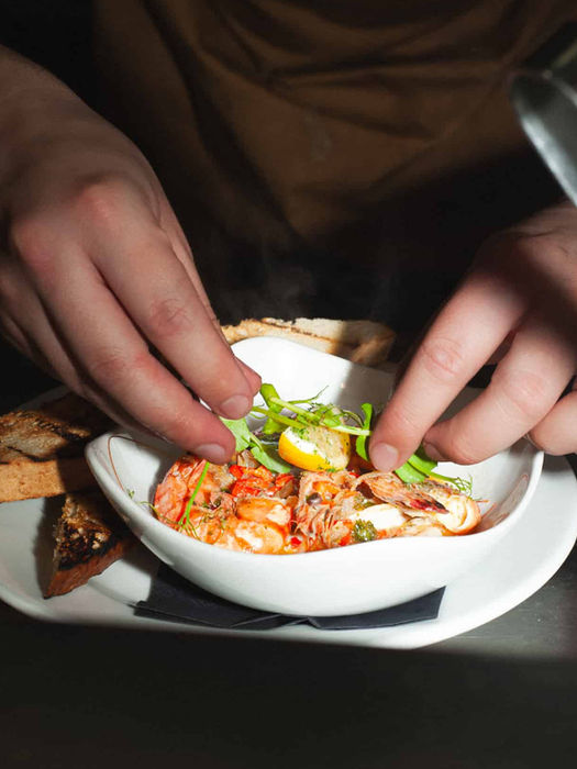 One of Casa's chef preparing a gambas pil pil with prawns and toast in the kitchen