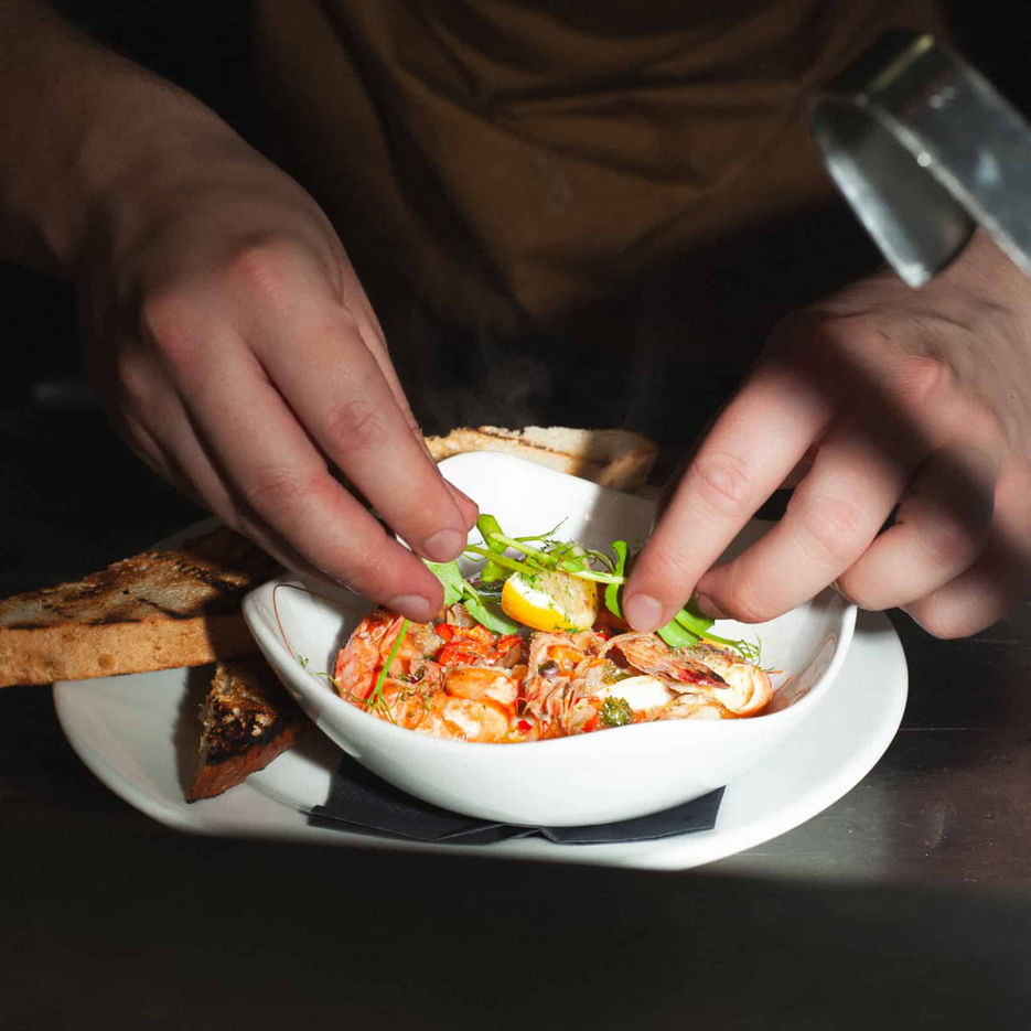 One of Casa's chef preparing a gambas pil pil with prawns and toast in the kitchen