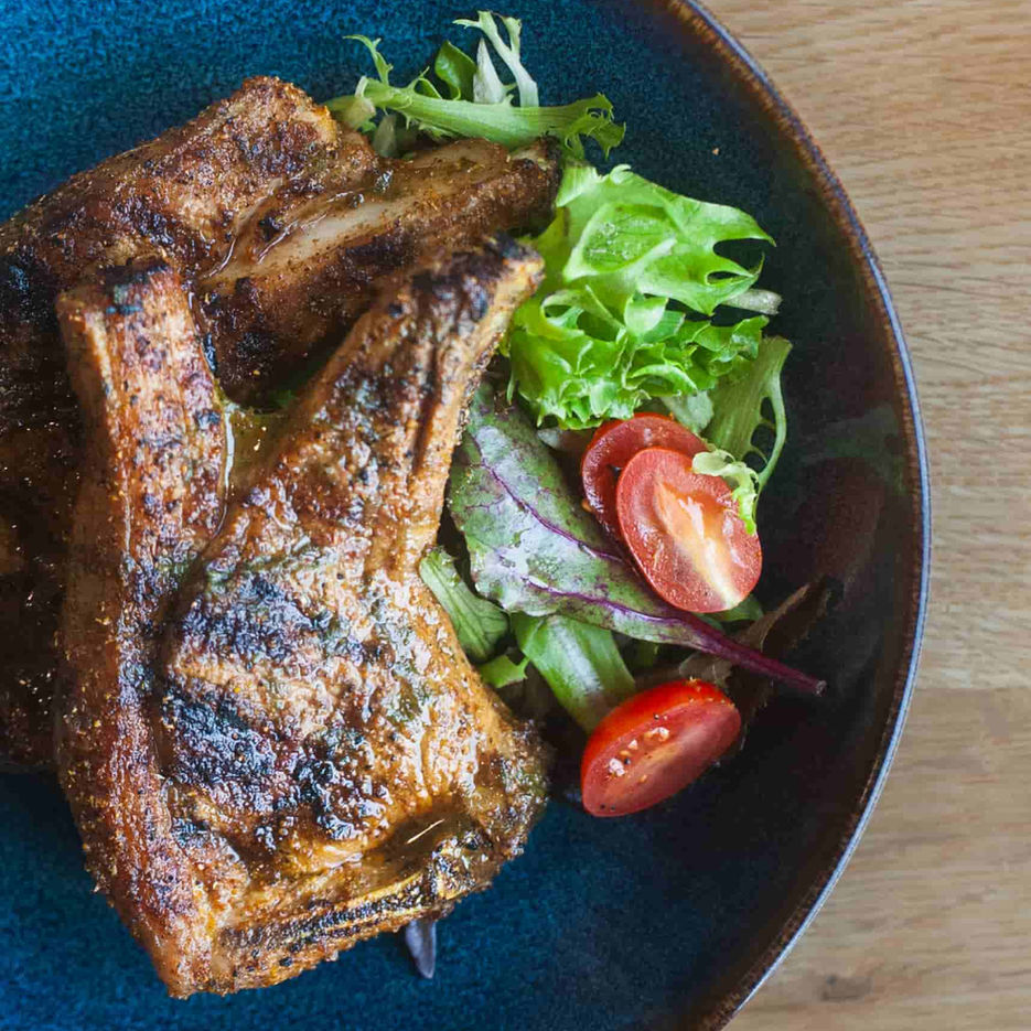 Casa's Moroccan style lamb chops served on blue plate with a side salad