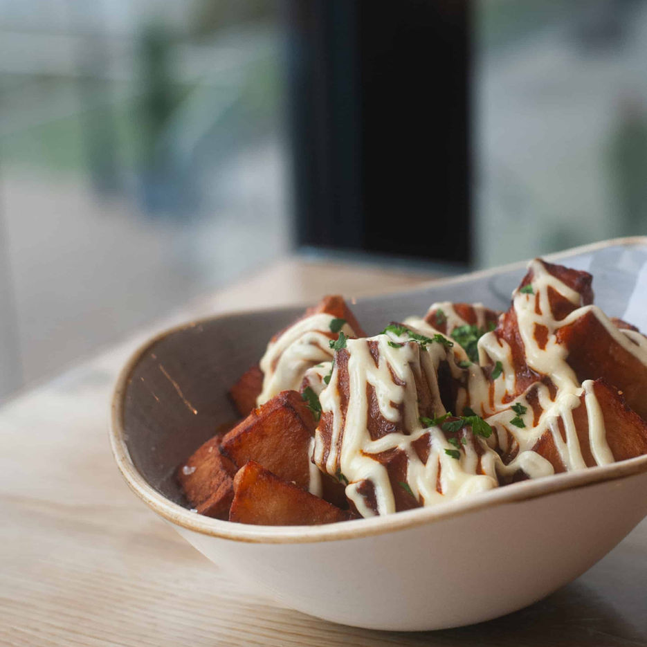 Casa's patatas bravas small plate dish on a table overlooking the lake