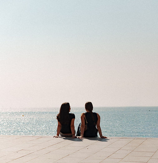 Two people sitting beside the sea in soft afternoon light.