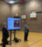 Two men presenting with a screen in a gymnasium