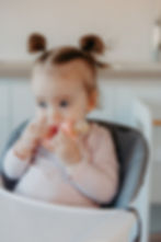 Baby in high chair eating from silicone baby food feeder