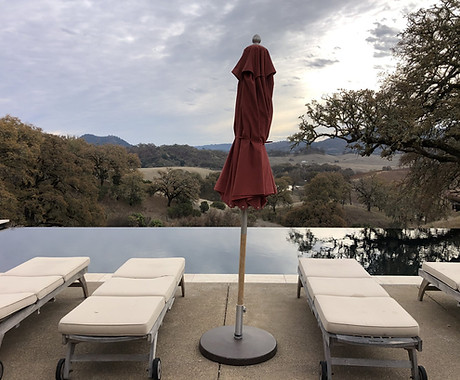 Hilltop pool deck with lounge chairs and umbrella overlooking Sonoma County