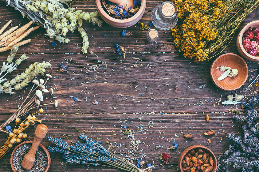 A serene wooden workspace adorned with a variety of herbs, flowers, and jars for tinctures, creating an inviting ambiance that reflects the holistic essence of Soma Ayurved.