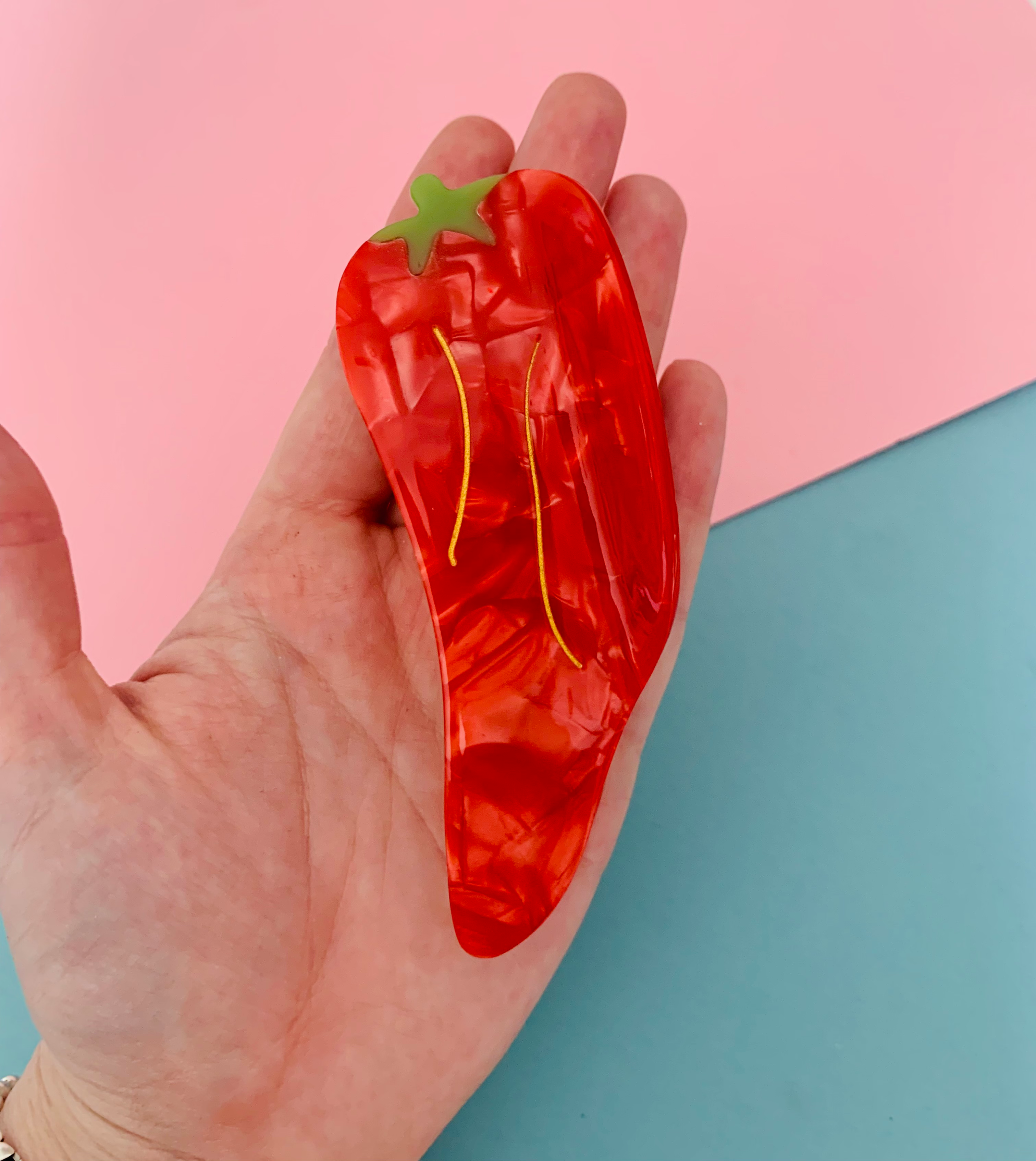 Hand holding Red chilli pepper hair claw