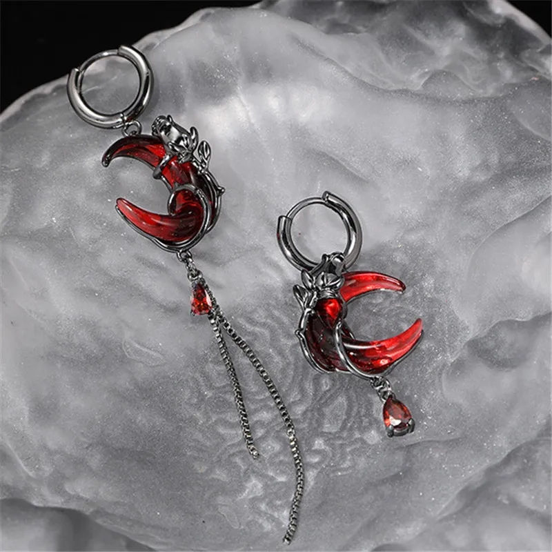 Asymmetrical metal alloy earrings with a gothic theme, featuring red crescent mo