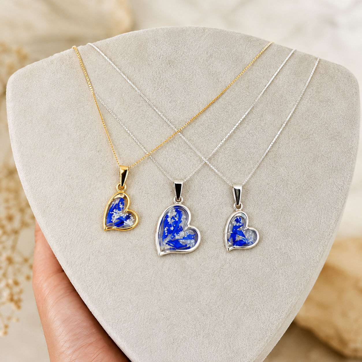 Selection of handcrafted gold-plated and 925 sterling silver blue and white Galilee botanical heart pendant necklaces on disp