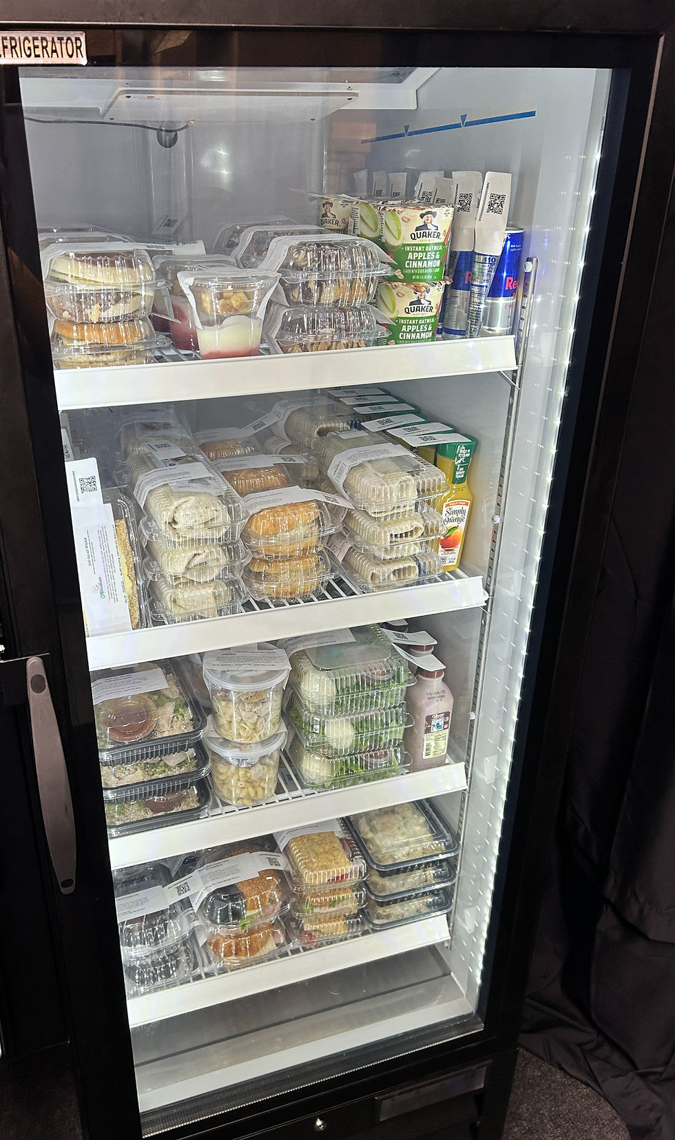 Eye-level view of a fresh food vending machine stocked with colorful salads and sandwiches