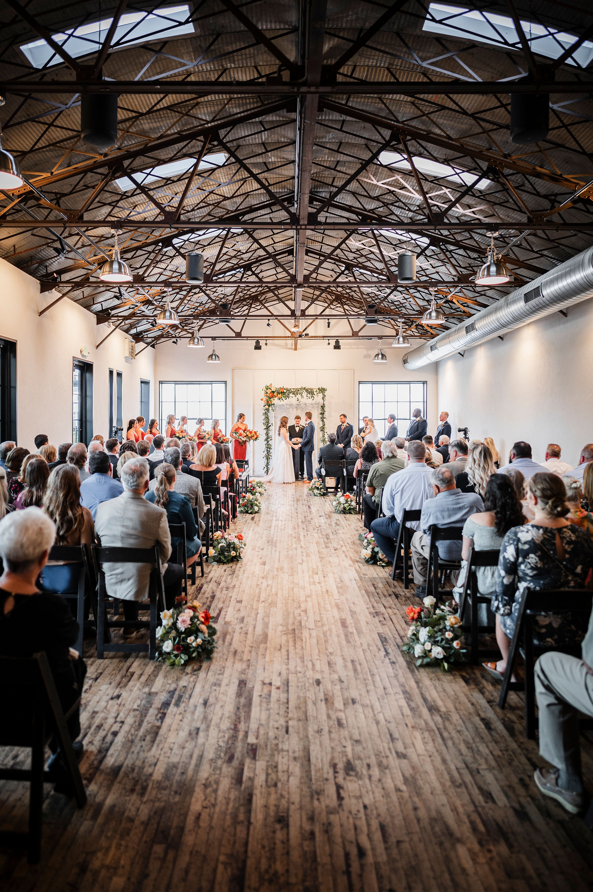 bride and groom at alter with guests seated during wedding ceremony at The Tin Smith in Madison Wisconsin
