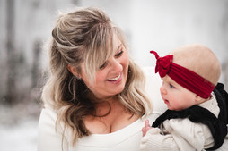 blonde mother holding her small baby in red headband outside in the snow in Deerfield Wisconsin