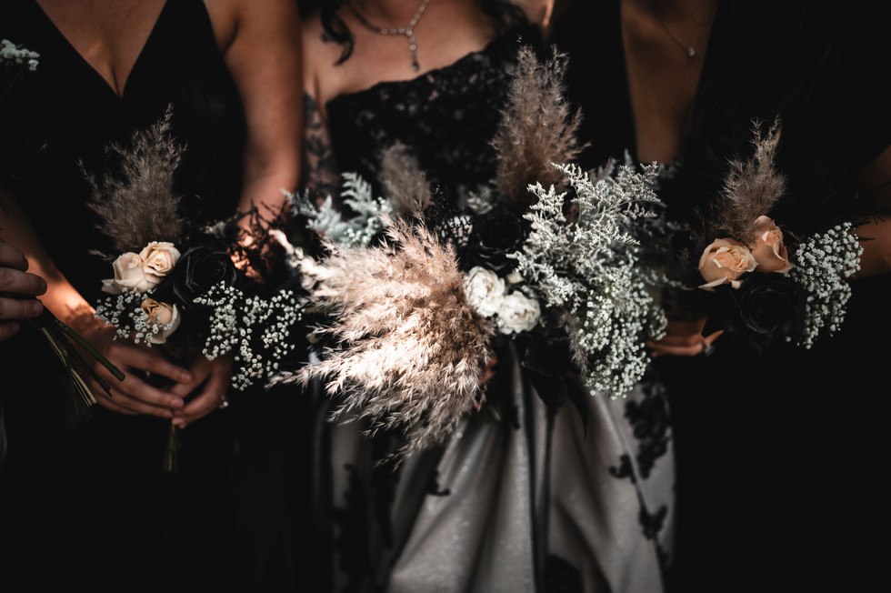 bride and bridesmaids in black dresses holding bouquets of flowers at Whispering Pines Event Center in Poynette Wisconsin