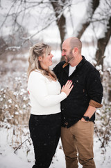 man in black shirt and woman in white sweater embracing outdoors in the snow in Deerfield Wisconsin
