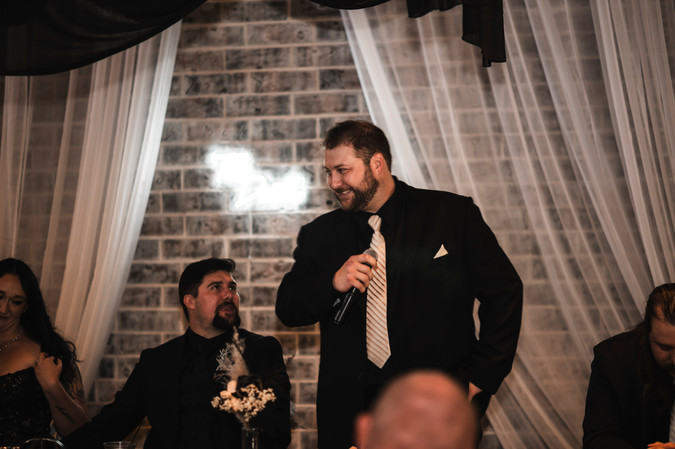 man giving speech at head table at wedding reception at Whispering Pines Event Center in Poynette Wisconsin