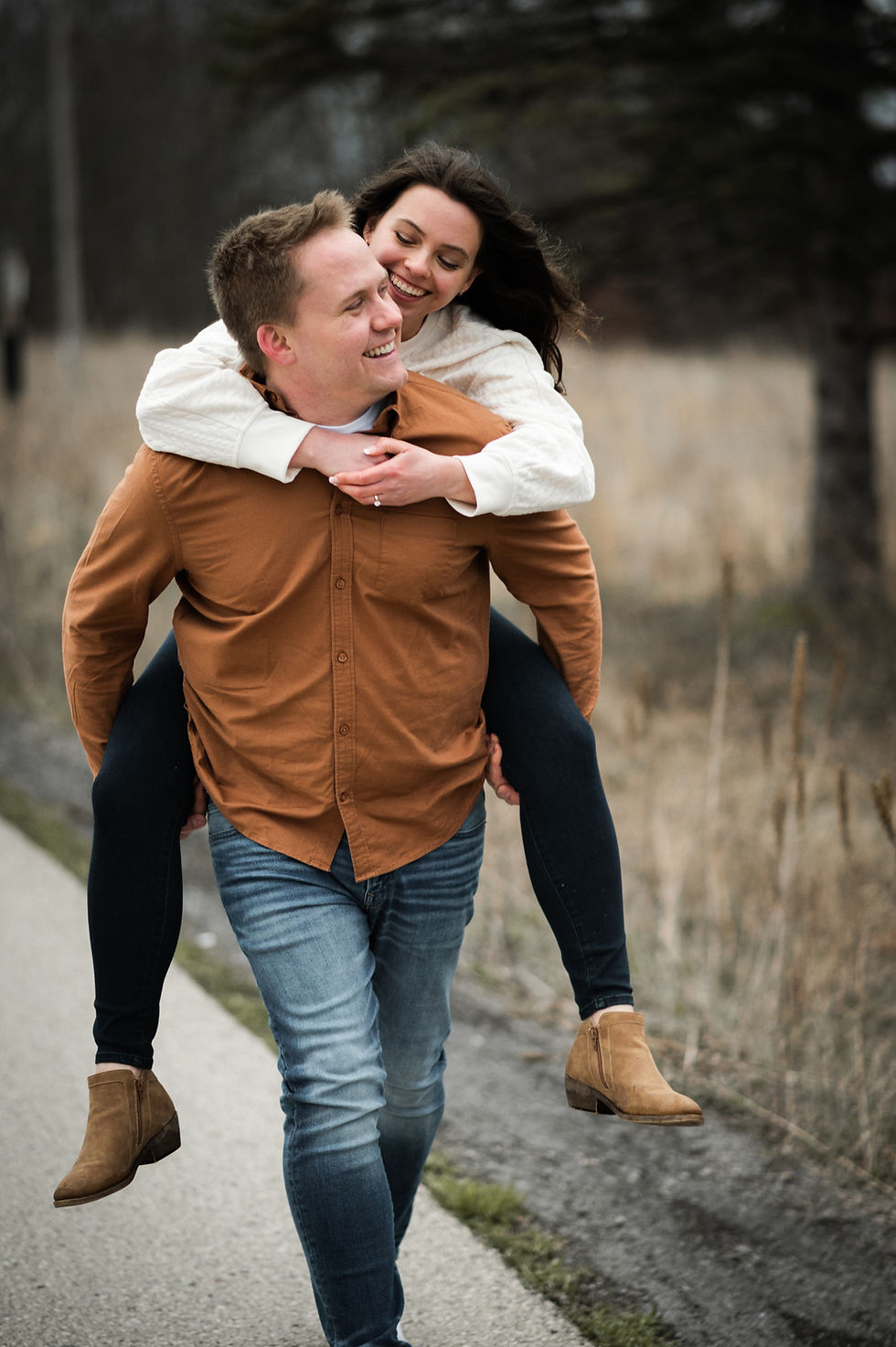 man giving woman a piggy back ride smiling outdoors at Retzer Nature Center in Waukesha Wisconsin