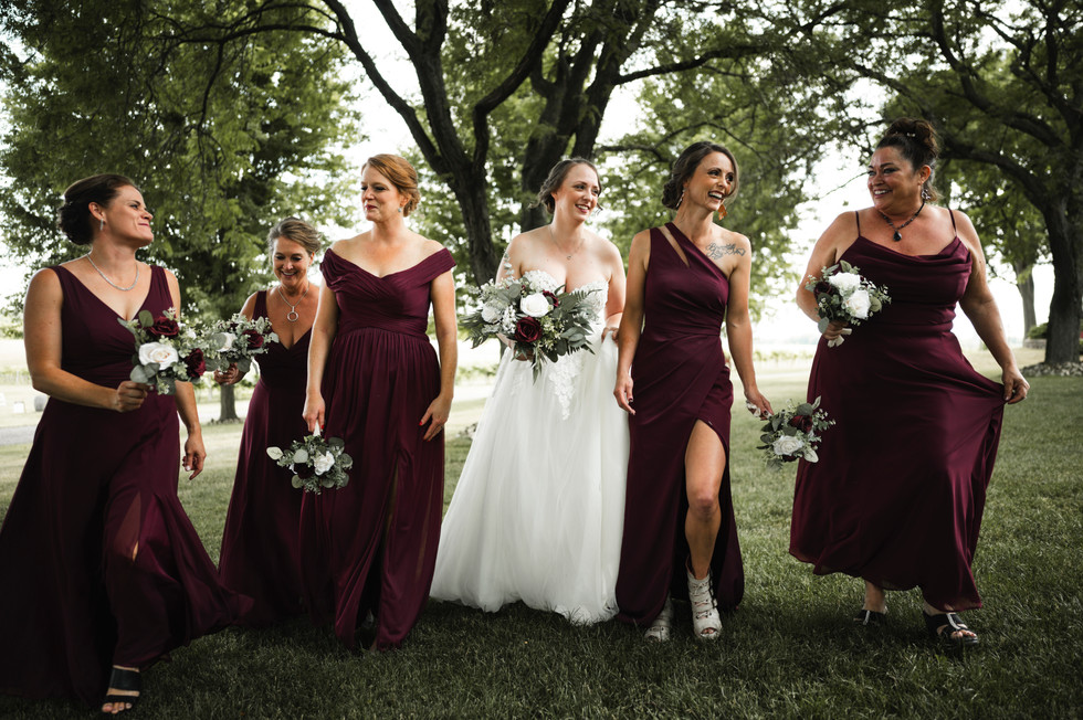 bridesmaids walking and smiling in green grass at Over The Vines in Edgerton Wisconsin