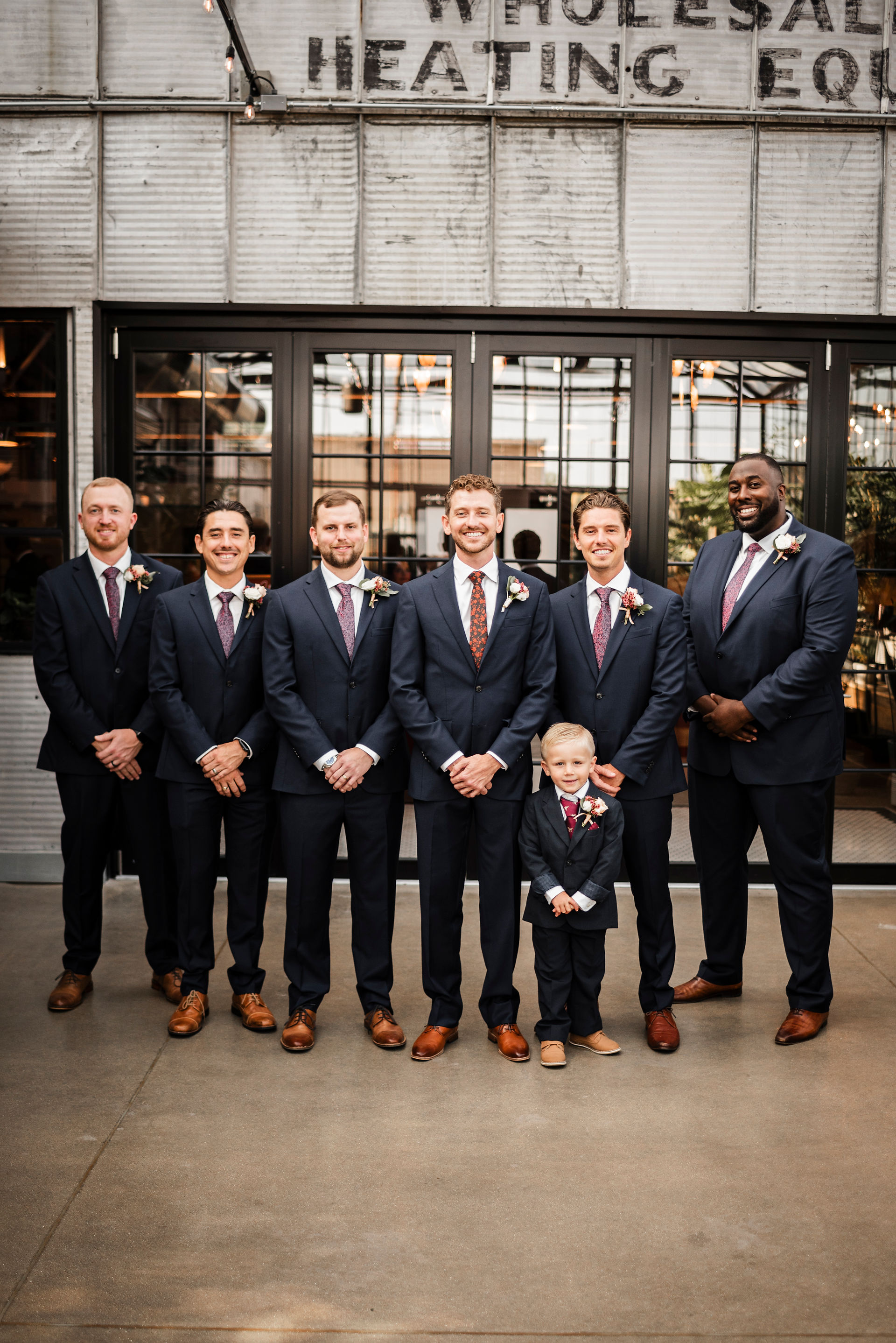 Groom and 6 groomsmen lined up in greenhouse at The Tin Smith in Madison Wisconsin