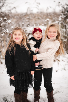 two small girls holding a baby outside in the snow in Deerfield Wisconsin
