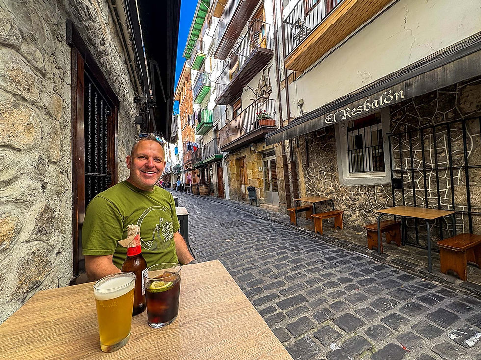 Man in green shirt smiles at a table with drinks on a cobblestone street. Background shows "El Resbalón" and colorful buildings.
AvVida.co.uk Adventure Motorcycle Travel
A quick bevvy on Calle de Nuestra Señora
Castro-Urdiales, Spain