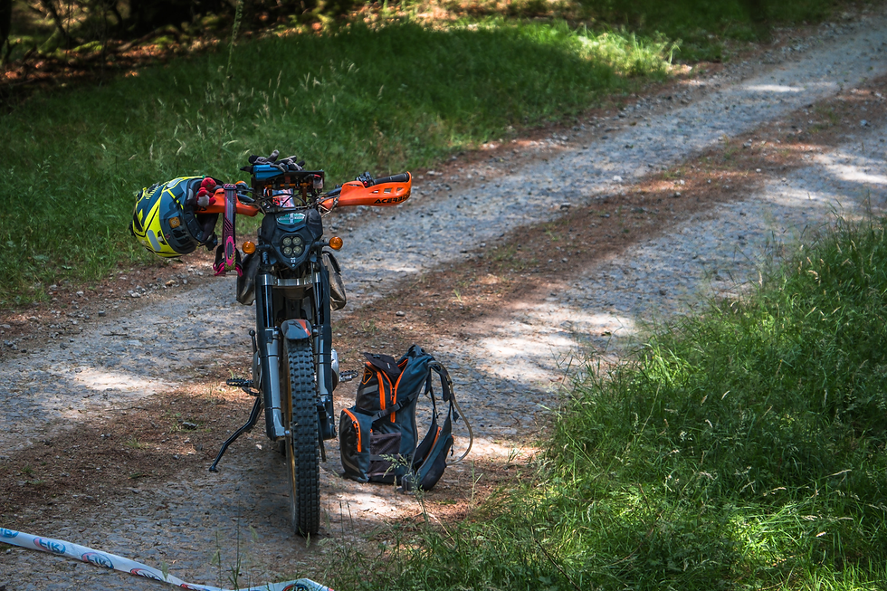 Off-road motorcycle with a yellow helmet and backpack parked on a gravel forest trail. Beacons Rally 2026 - ACU British Bike Rally Championship.
