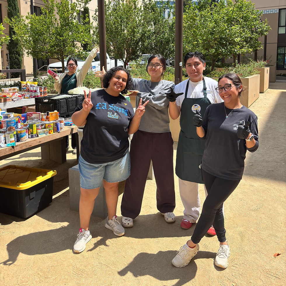 A group of enthusiastic volunteers at a food drive event, posing happily in front of a well-stocked table filled with canned goods and other food items, ready to support their community.