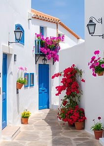 Typical street in a white village in spain, with blue doorways and beautiful colour flower