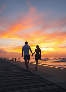 couple walking hand in hand along a boardwalk by the beach with a beautiful colourful suns