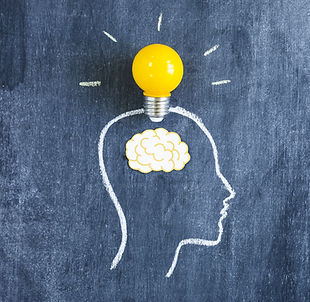 Human head drawn with chalk and a lightbulb and paper brain overlayed.