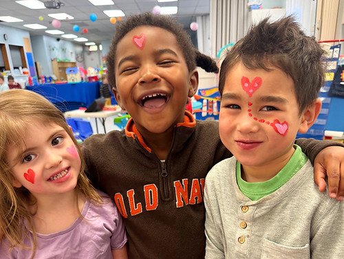 Three preschoolers with painted faces laughing together in a Hummingbird Preschool classroom