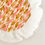 Thumbnail: Detail of finalised LYKKE DIY cushion in peach curry dark yellow orange ribbon colours