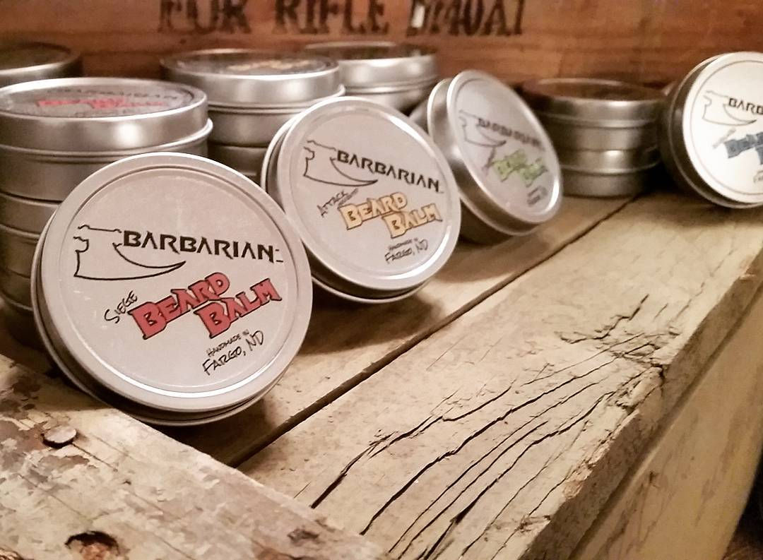 A wooden shelf with tins of different scented Barbarian brand beard balms