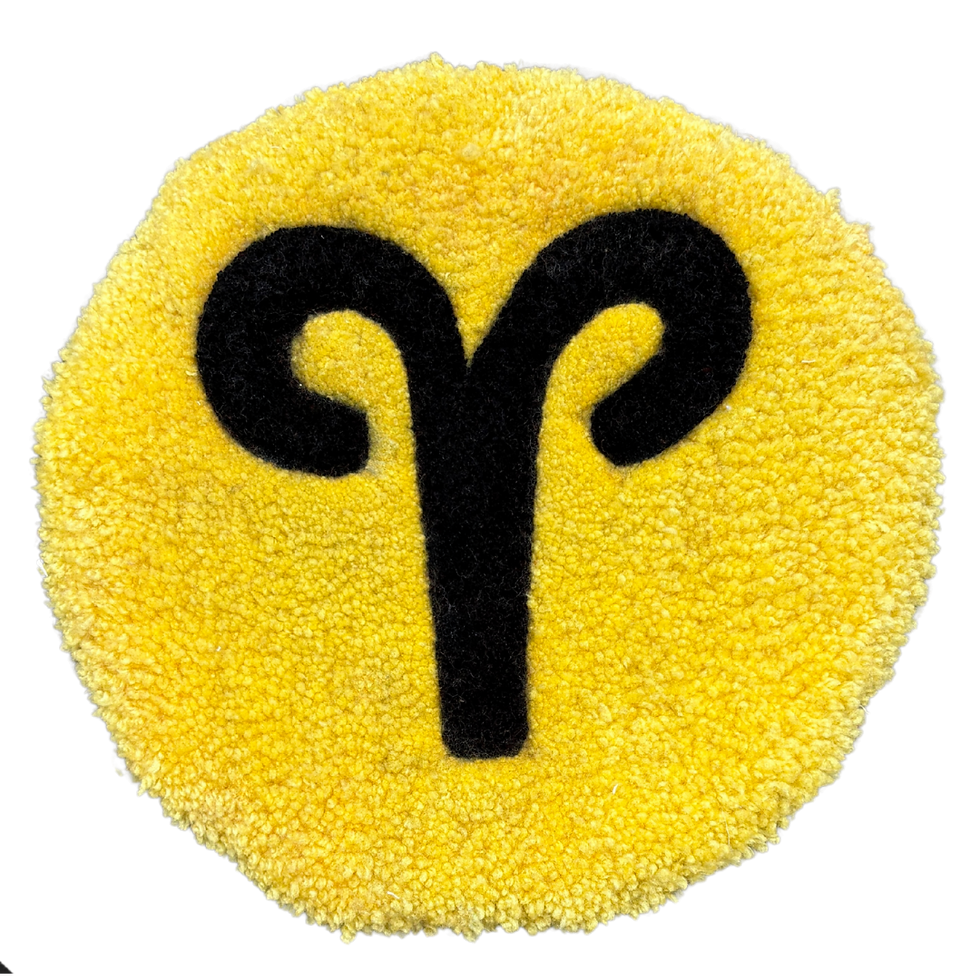A 33cm circular hand-tufted Aries glyph in vibrant yarn, featuring the minimalist ram horn symbol with soft cut-pile texture